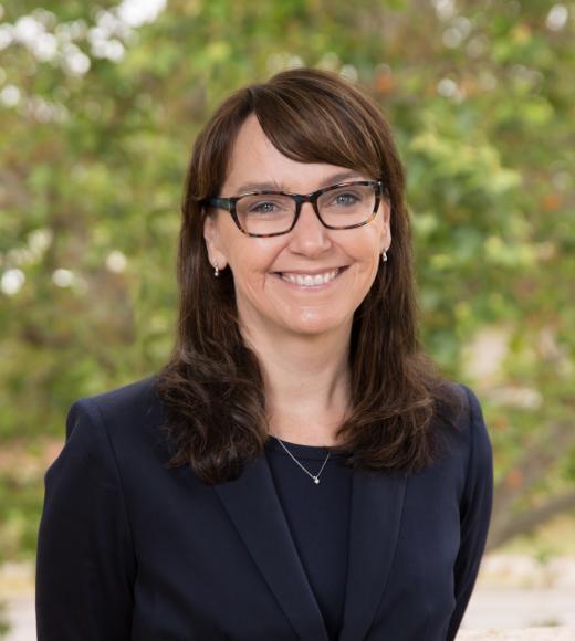 Picture of Dr. McAllister with glasses, green background, black blazer